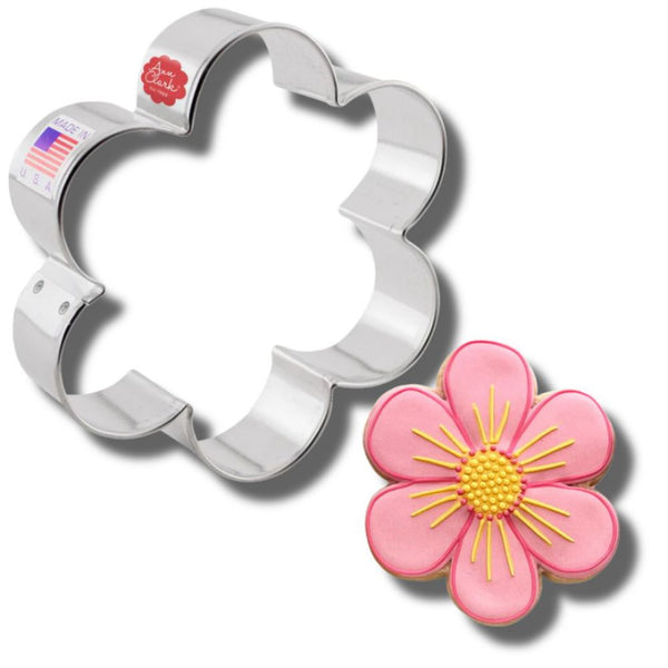 Flower-themed cookie cutter by Ann Clark with a beautifully decorated pink cookie, showcasing precision craftsmanship.